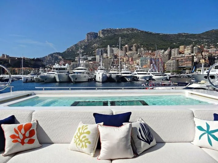 a lounge chair on a beach with boats in the water and a city in the background aboard STARBURST IV Yacht for Charter