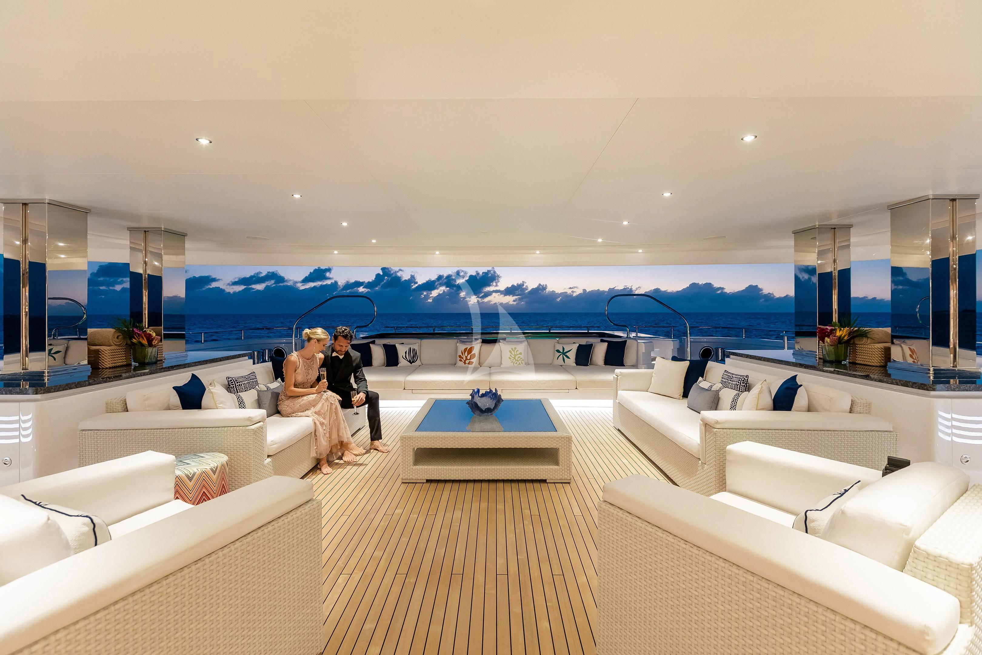 a couple sitting on a bench in a large room with white couches aboard STARBURST IV Yacht for Charter