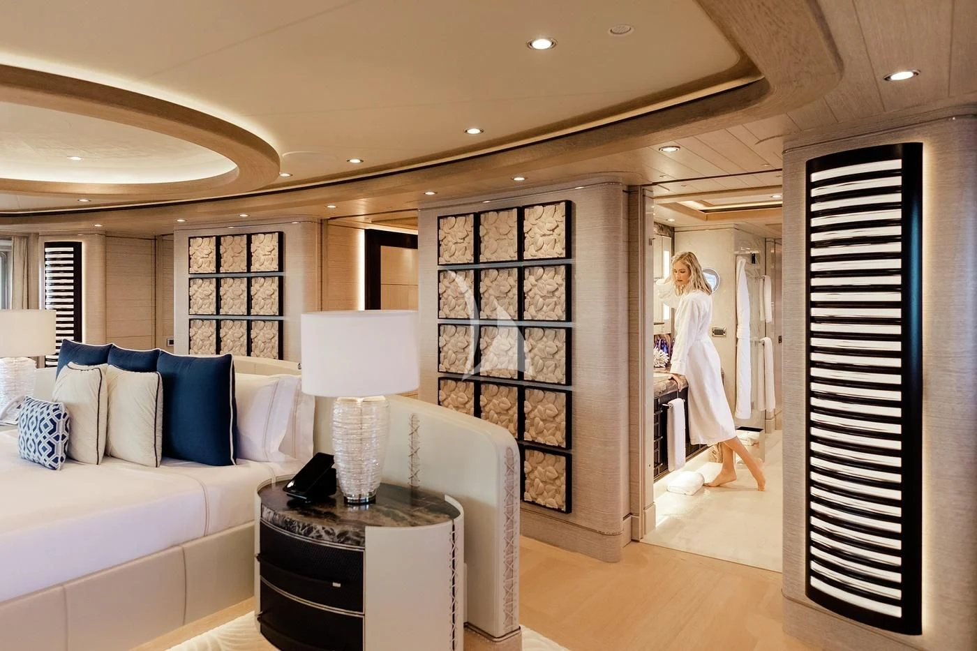 a person in a white dress in a room with a bed and a table and a lamp aboard STARBURST IV Yacht for Charter