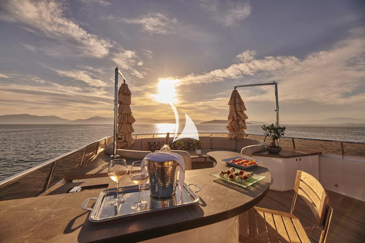 a table with a candle and a glass with a body of water in the background aboard PROMETHEUS I Yacht for Charter