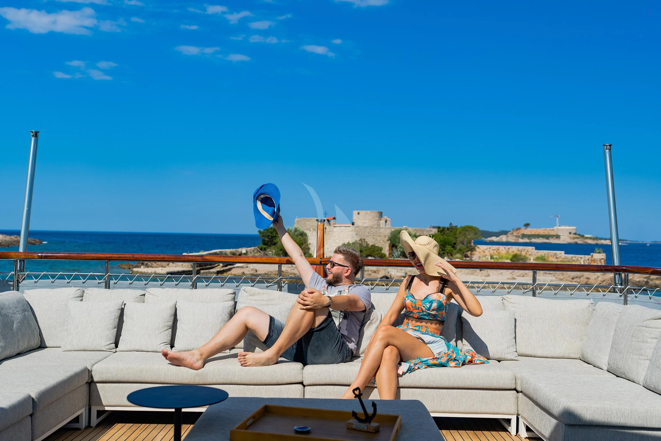 a man and woman sitting on a couch with a frisbee aboard VALENTINA II Yacht for Sale