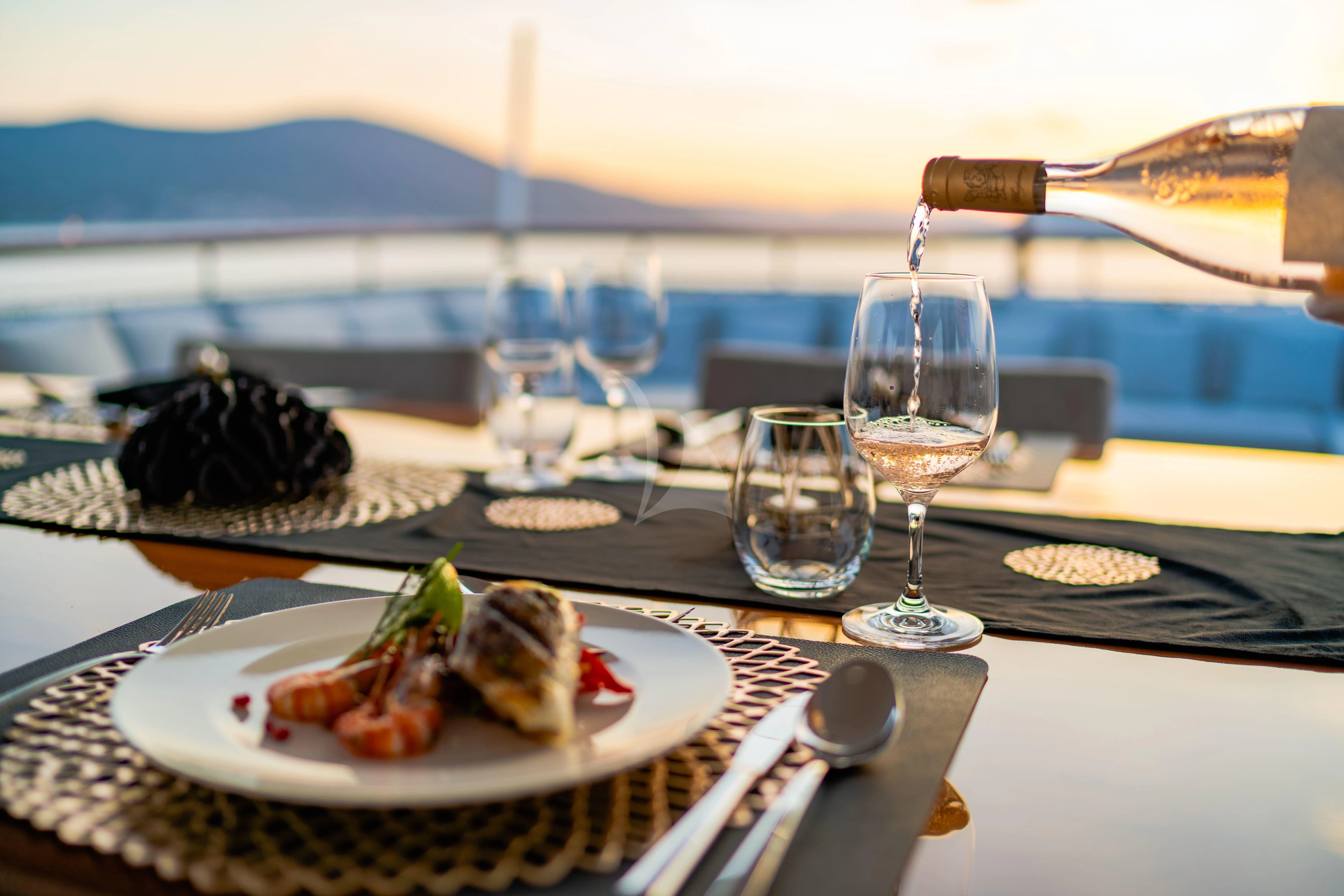 a plate of food and wine aboard VALENTINA II Yacht for Sale