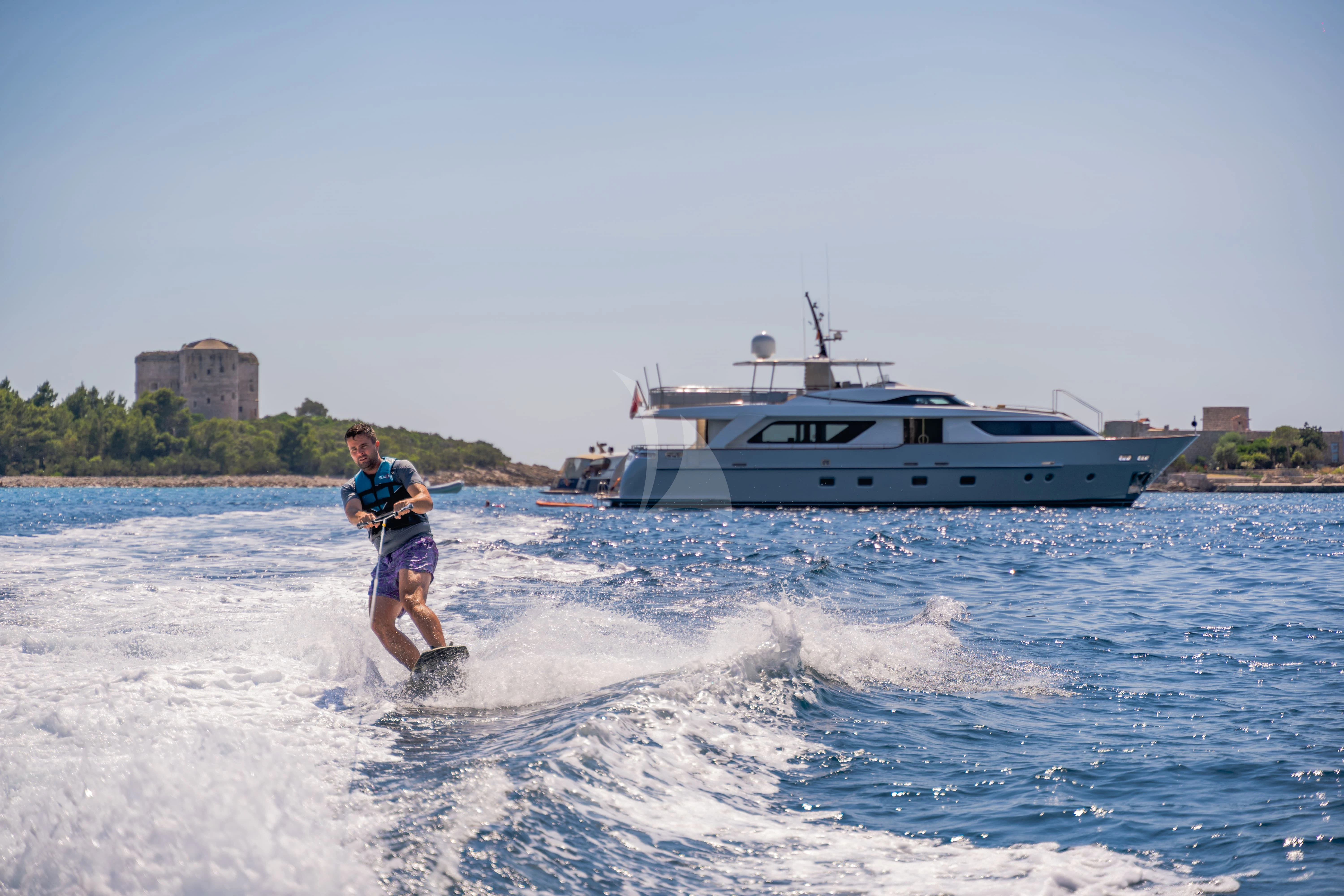 a man water skiing in front of a boat aboard VALENTINA II Yacht for Sale