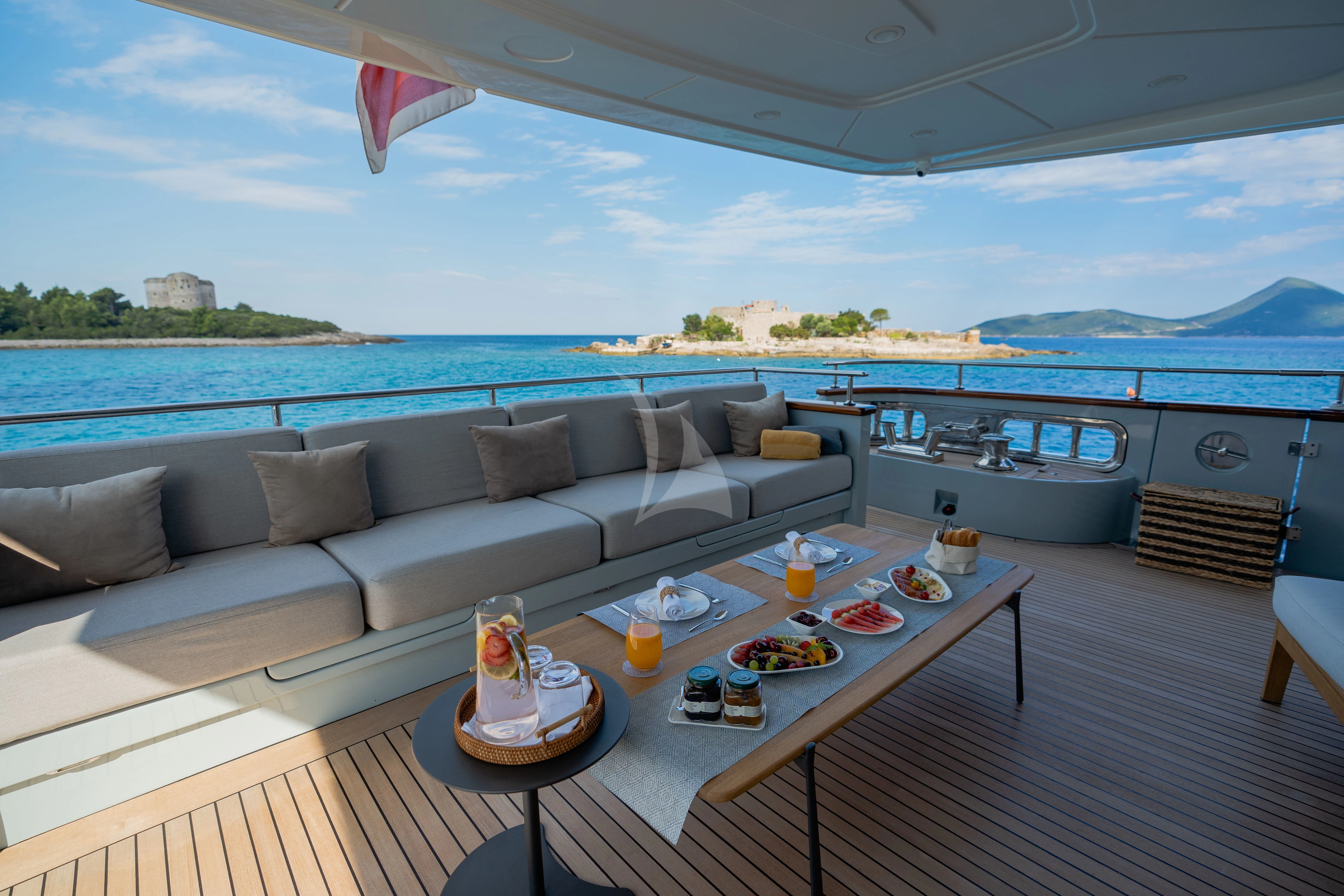 a living room with a large sofa and a table with food on it aboard VALENTINA II Yacht for Sale