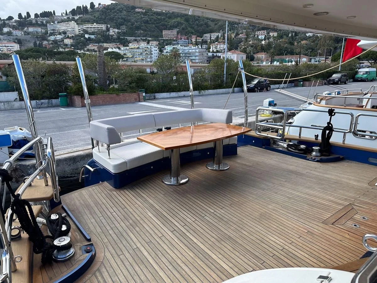 a wood deck with a table and benches on it aboard CHARISMA II Yacht for Sale