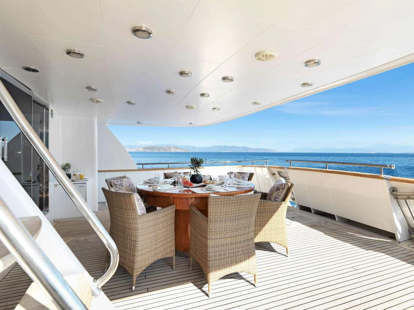 a table and chairs on a balcony overlooking the ocean aboard IDYLLE Yacht for Sale