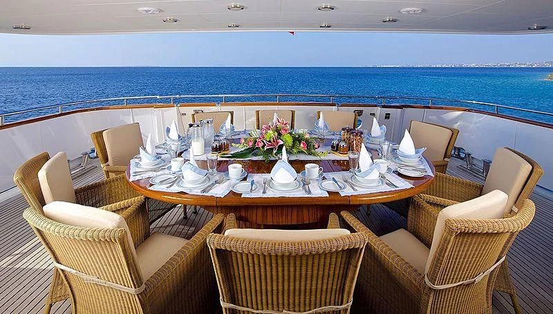 a table set for a meal on a balcony overlooking the ocean aboard IDYLLE Yacht for Sale