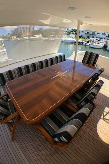a large wooden table with chairs on it next to a large window aboard ESCAPE Yacht for Sale
