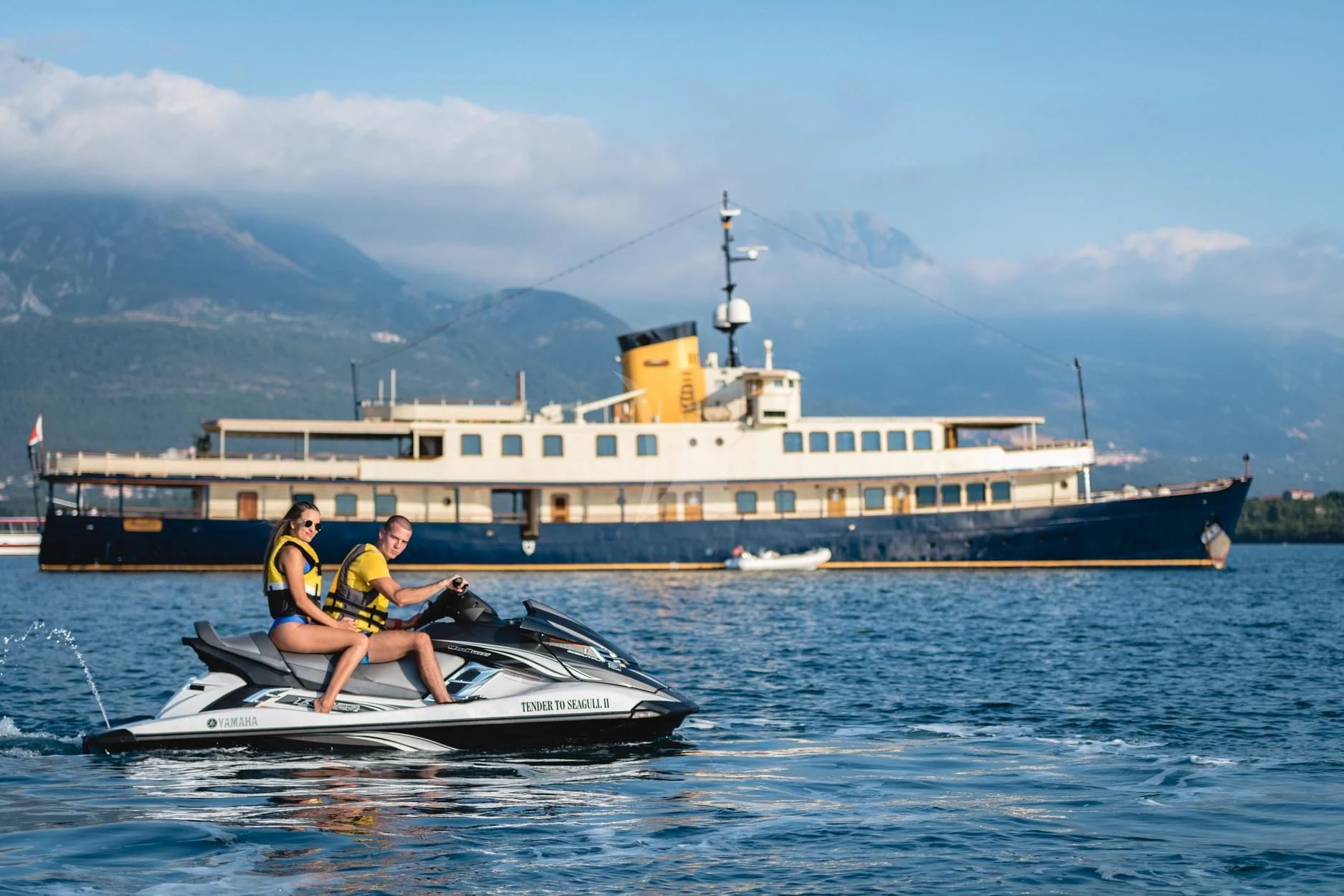 a couple of people on a boat in the water with a large cruise ship in the background aboard SEAGULL II Yacht for Sale