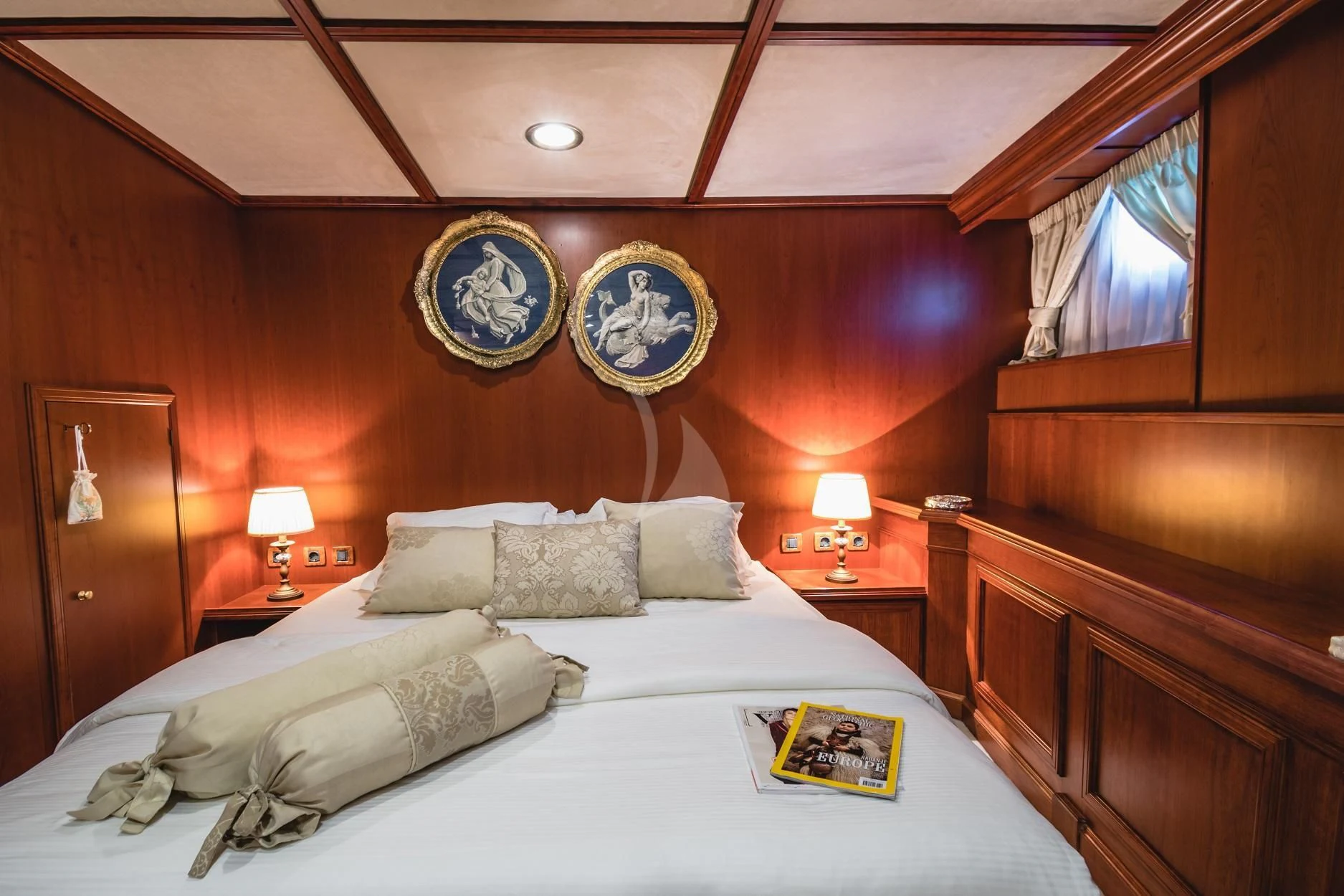 a bed with a white sheet and pillows in a room with a mirror aboard SEAGULL II Yacht for Sale