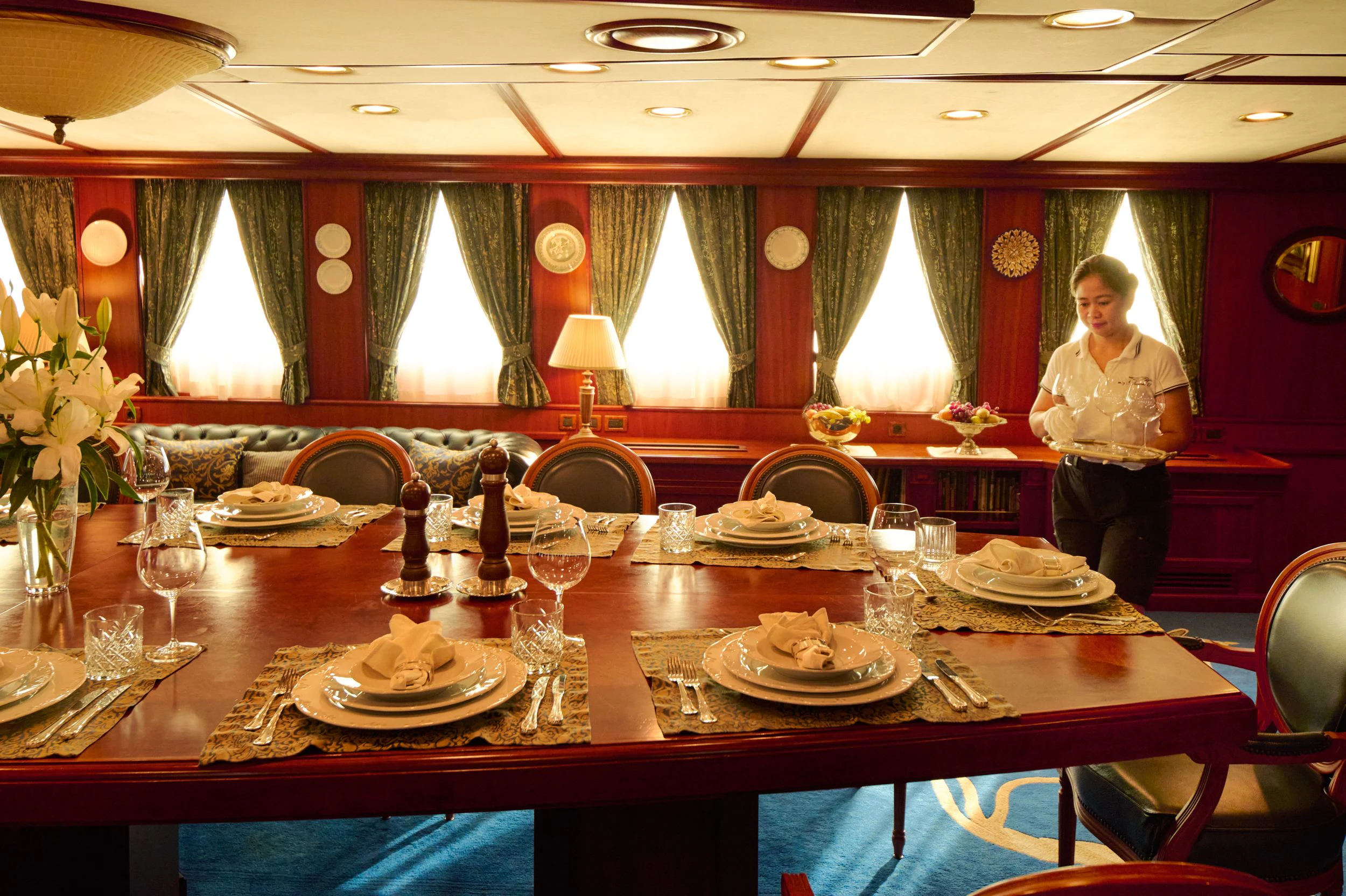 a person standing behind a table with plates and glasses on it aboard SEAGULL II Yacht for Sale