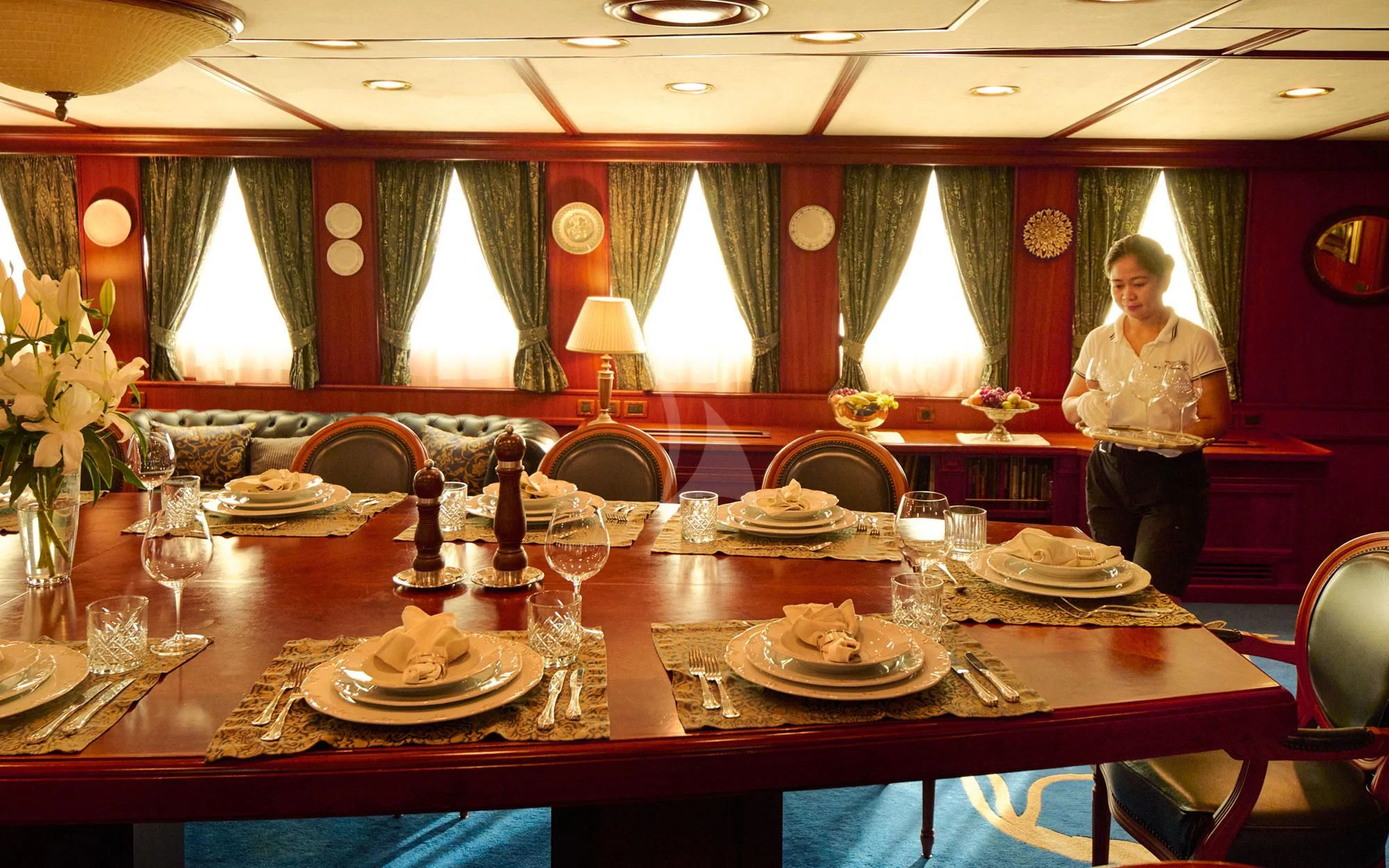 a person standing behind a table with plates and glasses on it aboard SEAGULL II Yacht for Sale