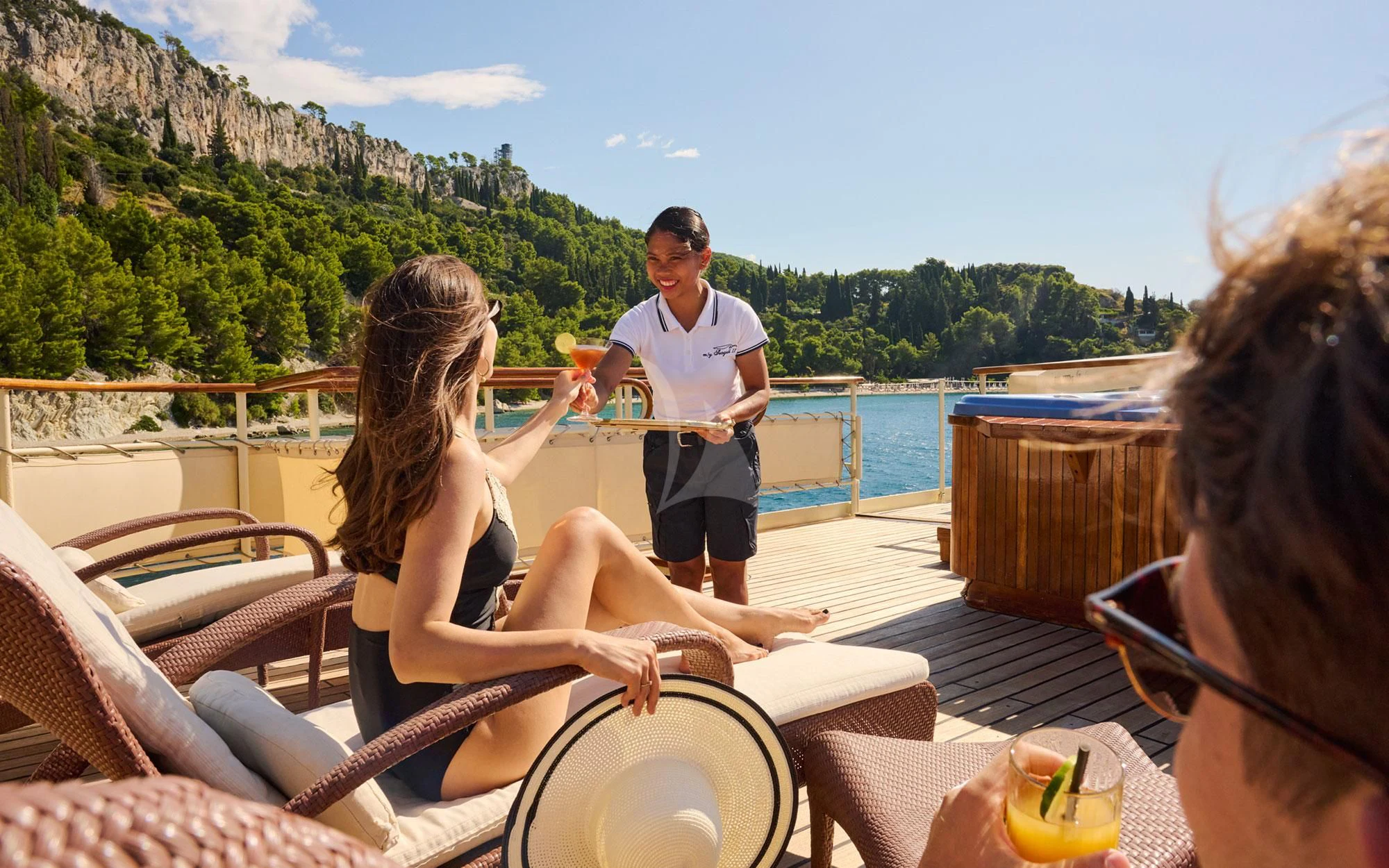 a group of people sitting on a deck with a body of water and trees in the background aboard SEAGULL II Yacht for Sale