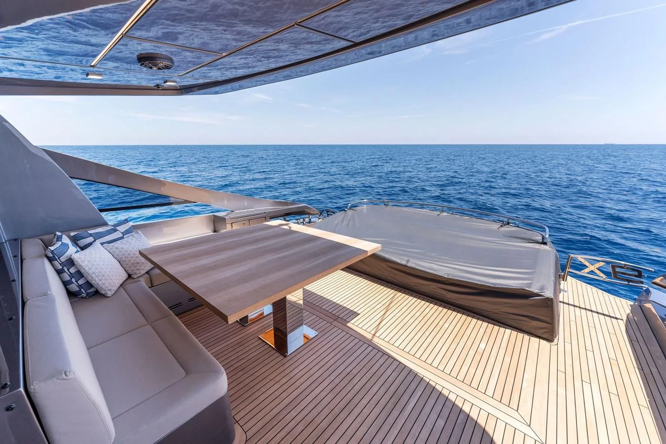 a deck with a table and chairs on it by the water aboard OUR TRADE Yacht for Sale