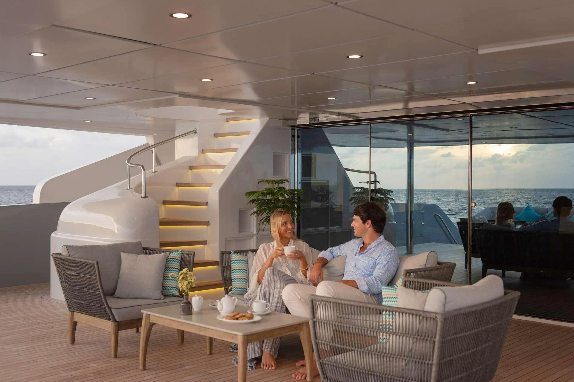a couple of people sitting in a room with a staircase and a glass wall aboard SEAREX Yacht for Sale