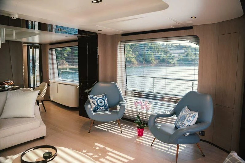 a living room with a blue chair and a large window aboard TAMUSIA Yacht for Sale