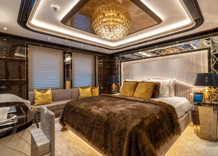 a large bedroom with a large chandelier above the bed aboard LEONA Yacht for Sale