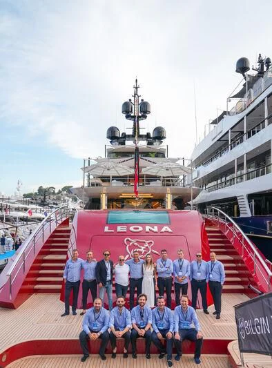 a group of people posing for a photo in front of a ship aboard LEONA Yacht for Sale