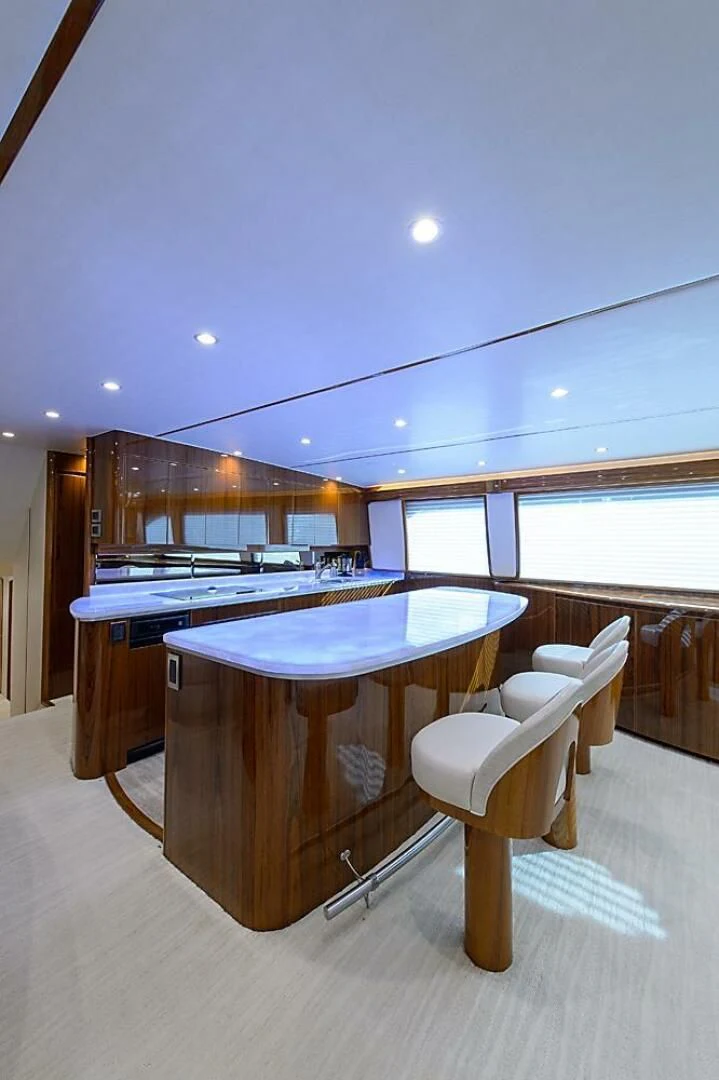 a large kitchen with a bar and chairs aboard INSTIGATOR Yacht for Sale