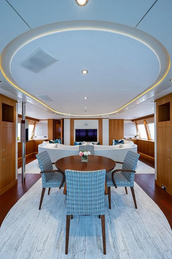 a large room with a table and chairs and a large round white umbrella aboard SHARKFINN Yacht for Sale