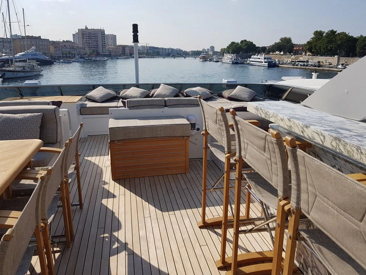 a deck with chairs and boats in the water aboard SHARKFINN Yacht for Sale