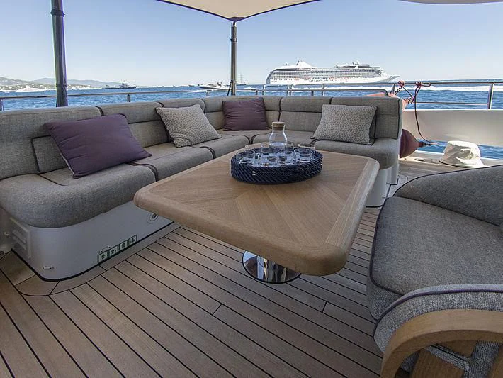 a couch and a table on a deck overlooking a body of water aboard SHARKFINN Yacht for Sale
