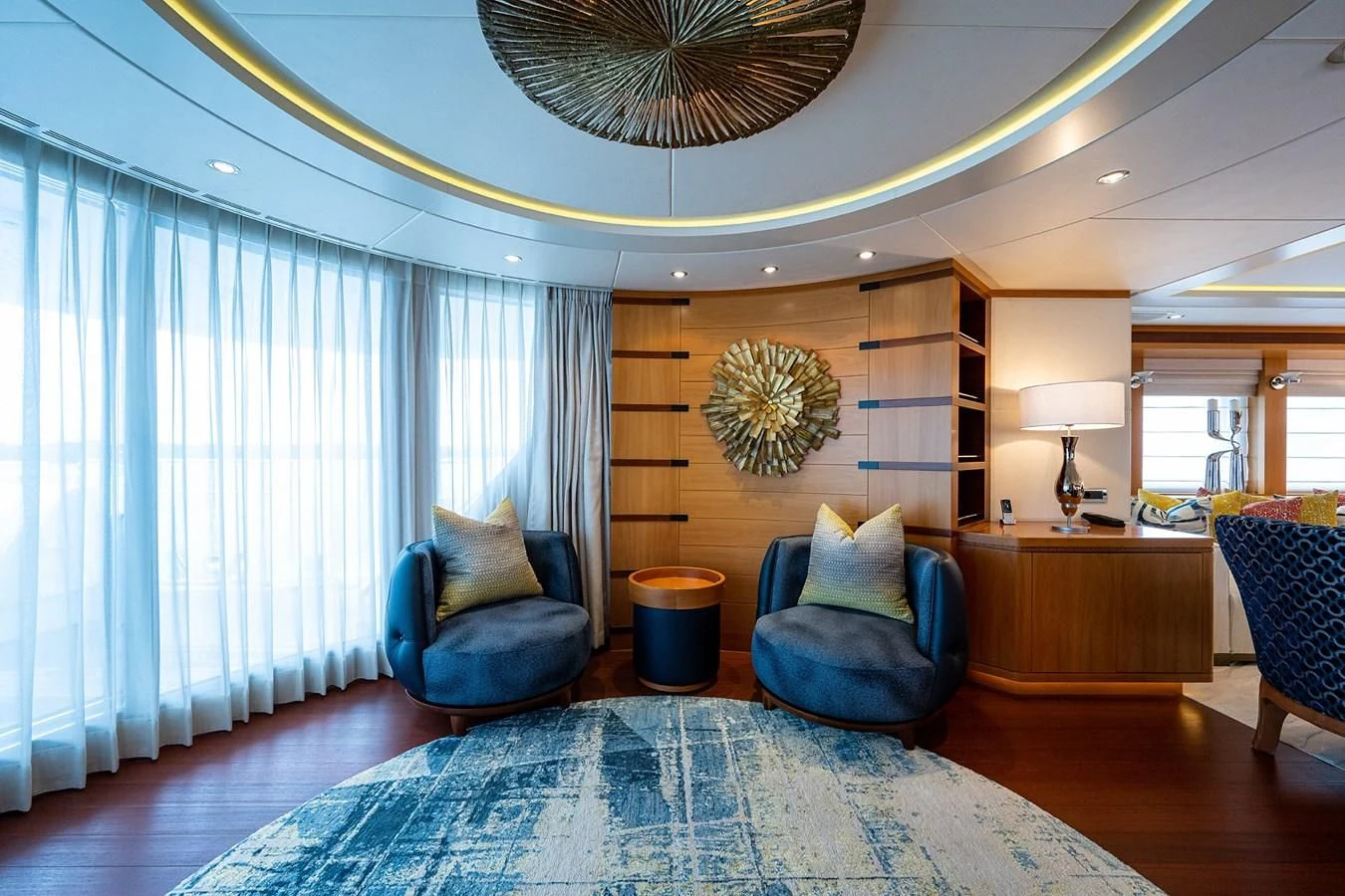 a large living room with a large blue chair and a chandelier aboard SHARKFINN Yacht for Sale