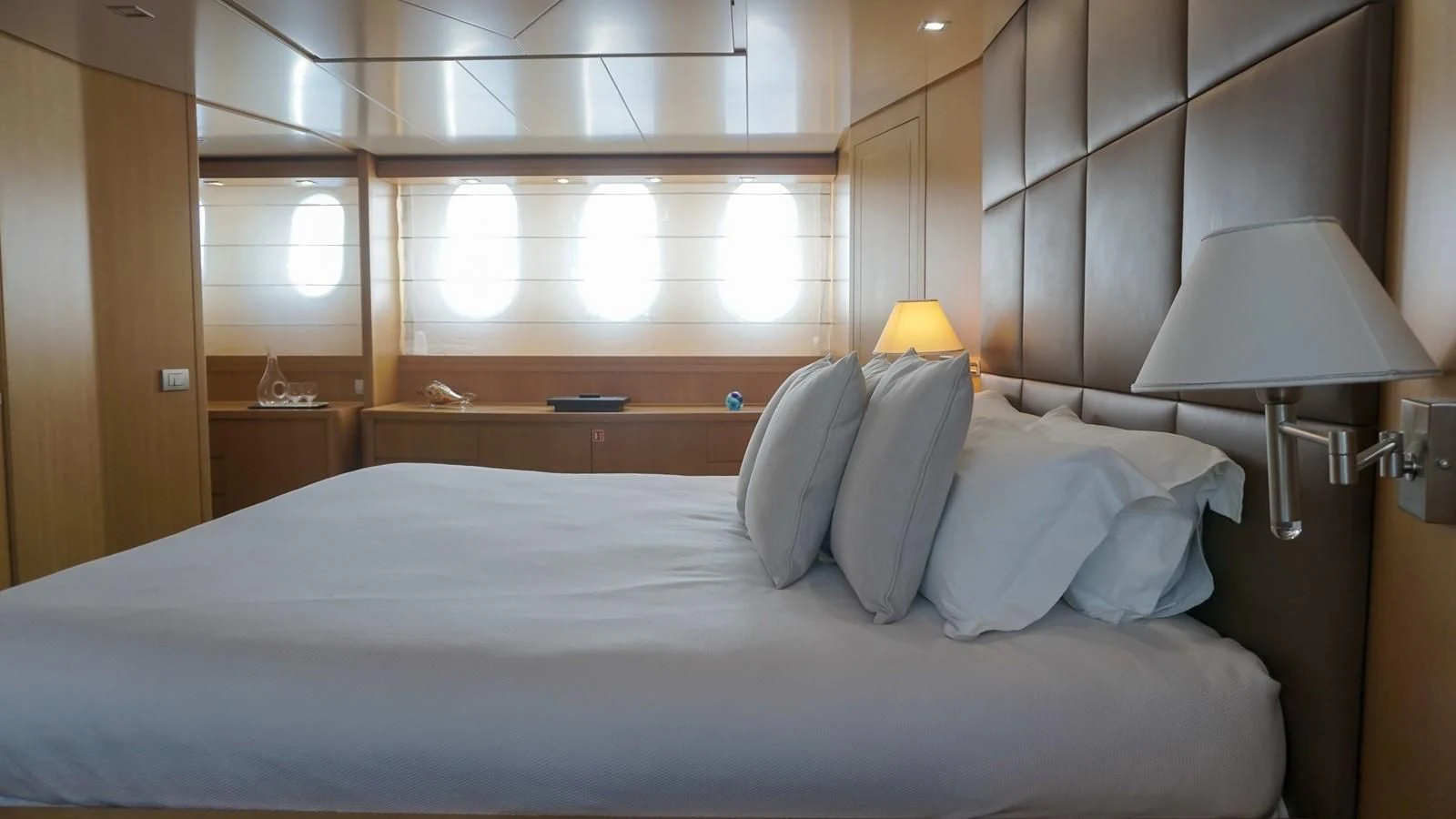 a bed with a white comforter and a lamp on it aboard PETRUS Yacht for Sale