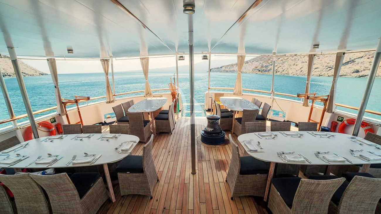 a deck with tables and chairs on it aboard EVOLUTION Yacht for Sale