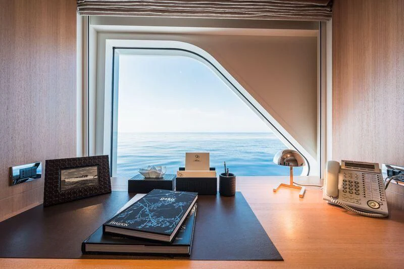 a room with a window and a table with books on it aboard GO Yacht for Sale