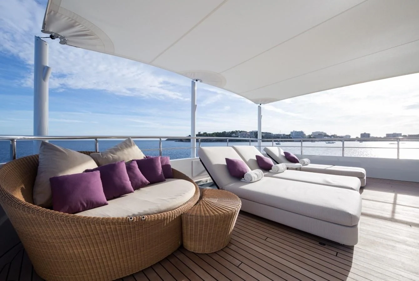 a large white bed next to a white couch and a white sofa aboard GO Yacht for Sale