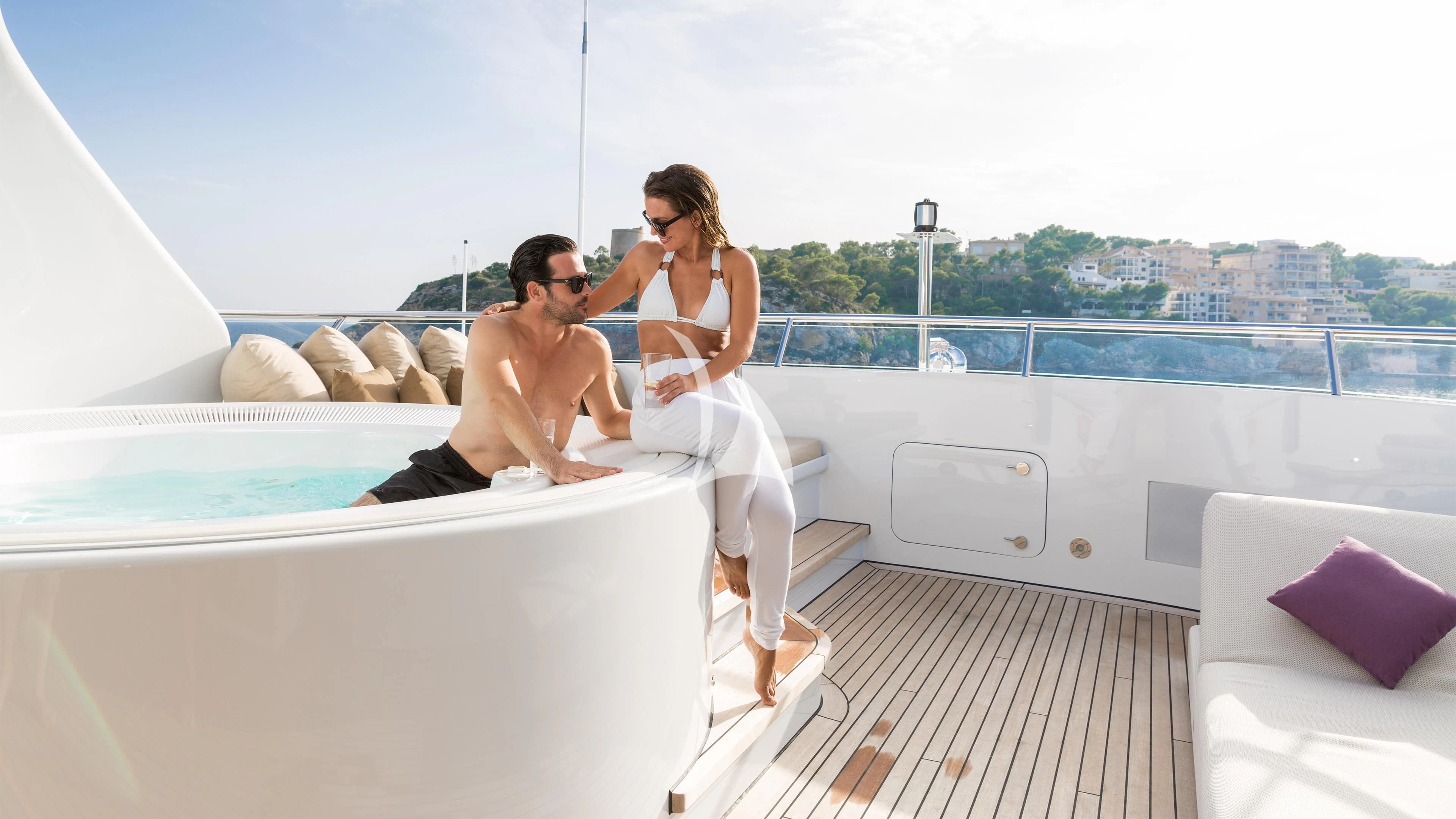 a man and woman sitting on a couch in a white bathtub aboard GO Yacht for Sale