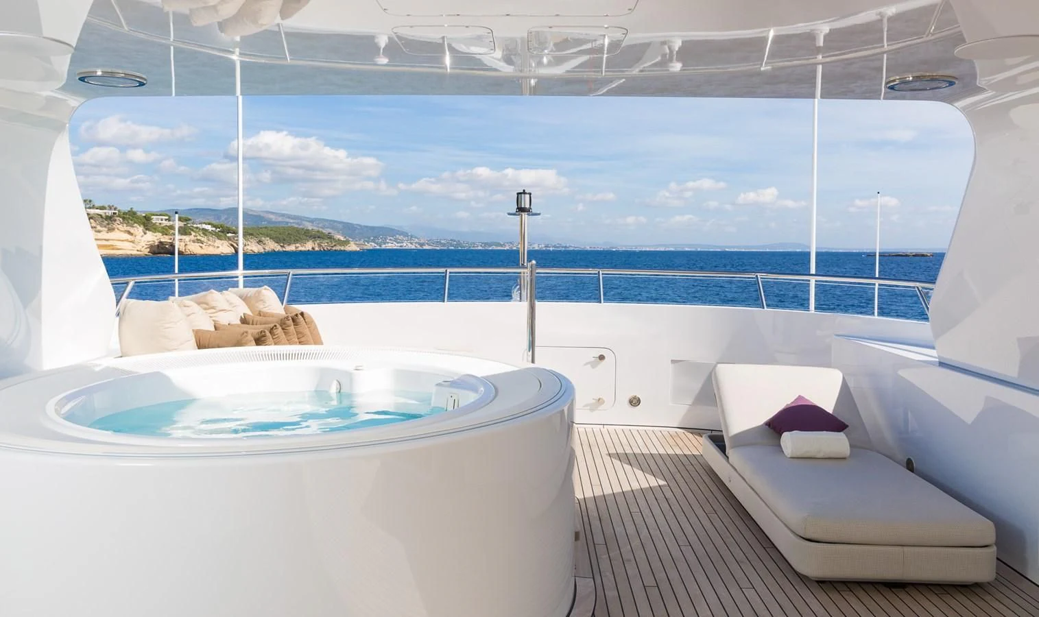 a large white bathtub with a view of the ocean and mountains aboard GO Yacht for Sale