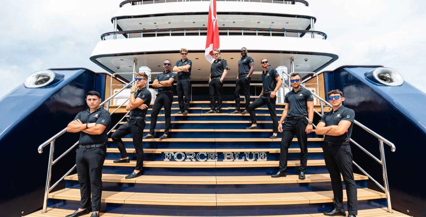 a group of people in uniform standing in front of a plane aboard FORCE BLUE Yacht for Charter
