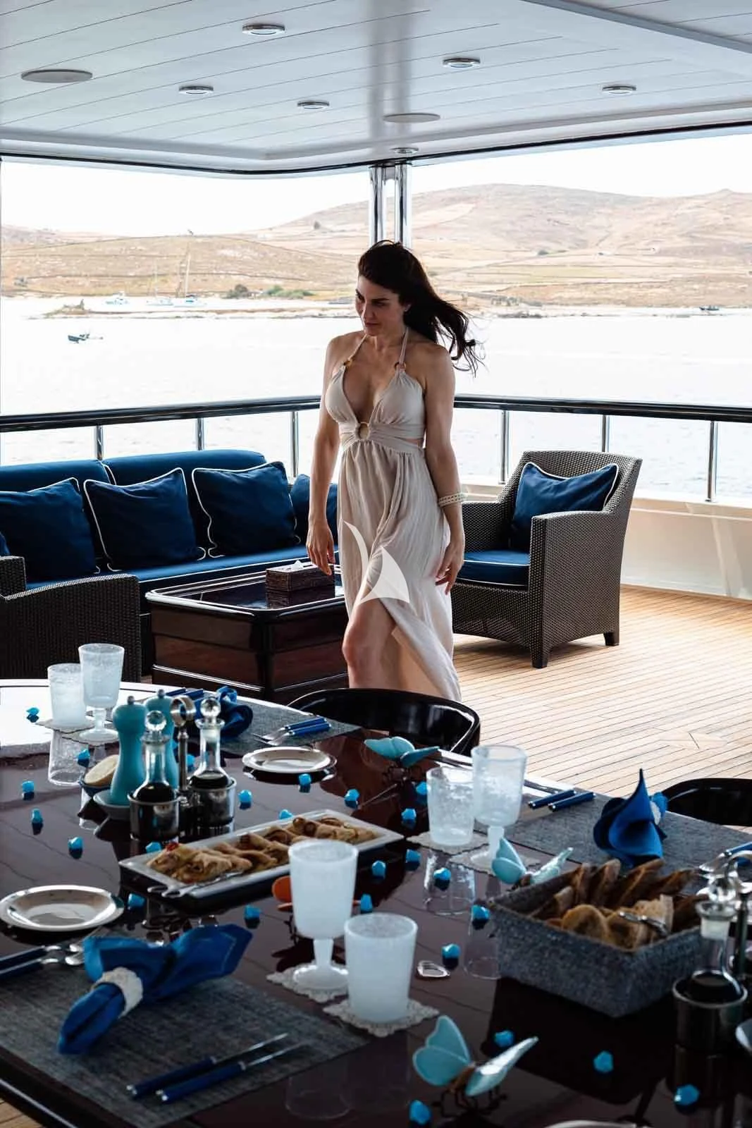 a person in a white dress standing in front of a table with food aboard FORCE BLUE Yacht for Charter