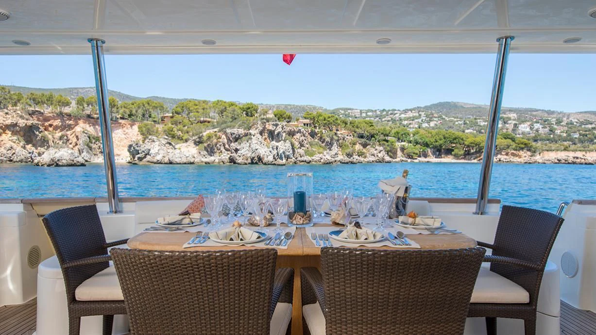a table set for a meal on a deck overlooking a large body of water aboard EOLIA Yacht for Sale