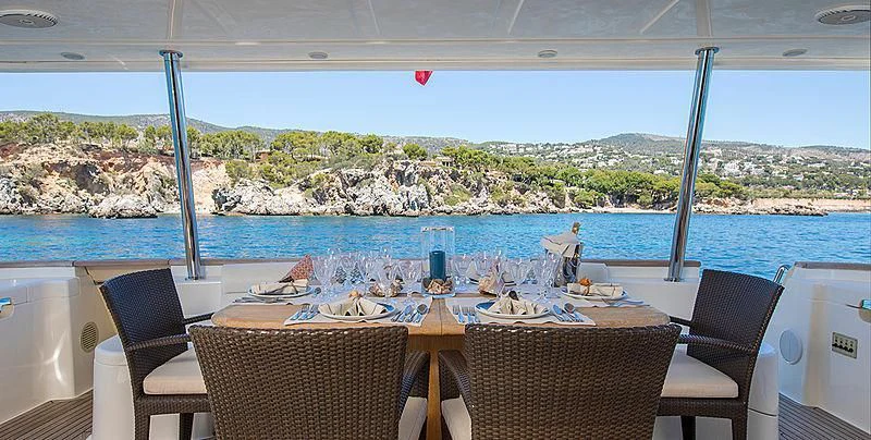 a table set for a meal on a deck overlooking a large body of water aboard EOLIA Yacht for Sale