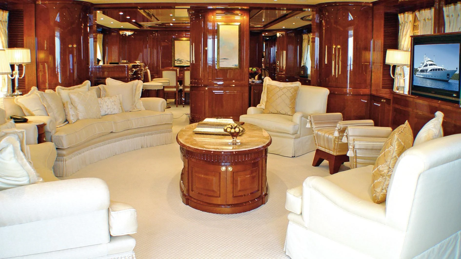 a living room with a large wood table and a television aboard AURA Yacht for Sale