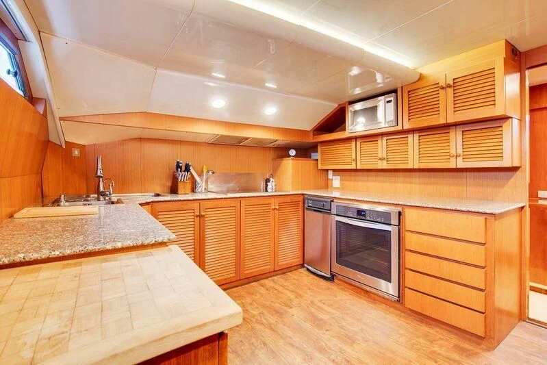 a kitchen with wooden cabinets aboard LE CANARD Yacht for Sale