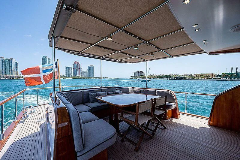 a deck with a table and chairs on it aboard CABALLERO Yacht for Sale