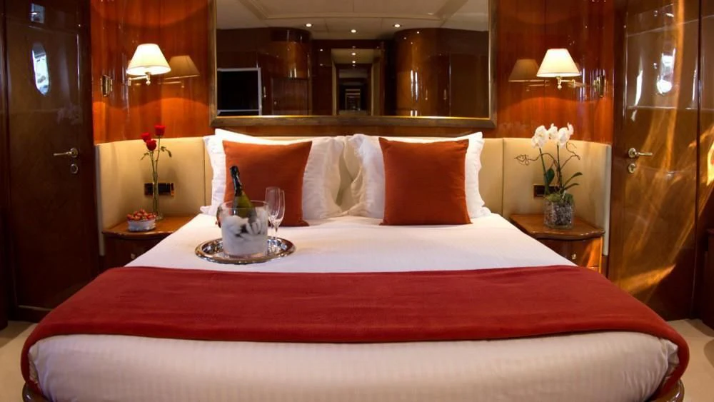 a bed with a red and white bed spread aboard CRISTALES Yacht for Sale