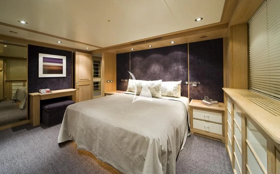 a bedroom with a bed and desk aboard CYAN Yacht for Sale