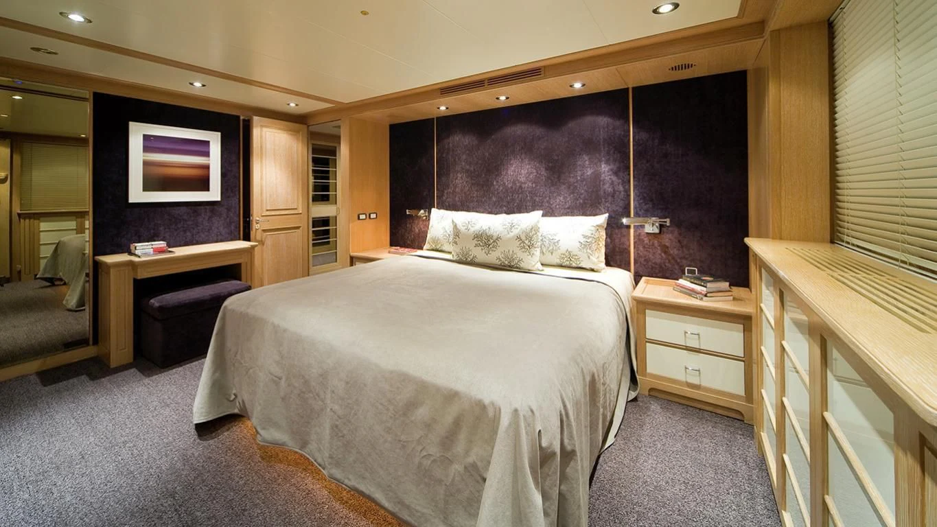 a bedroom with a bed and desk aboard CYAN Yacht for Sale