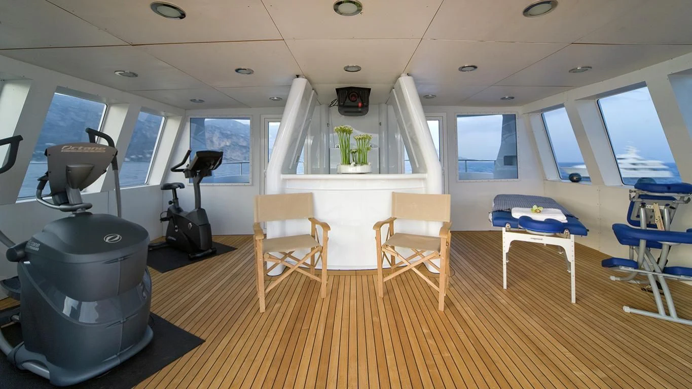 a room with a bed and a table and chairs aboard CYAN Yacht for Sale