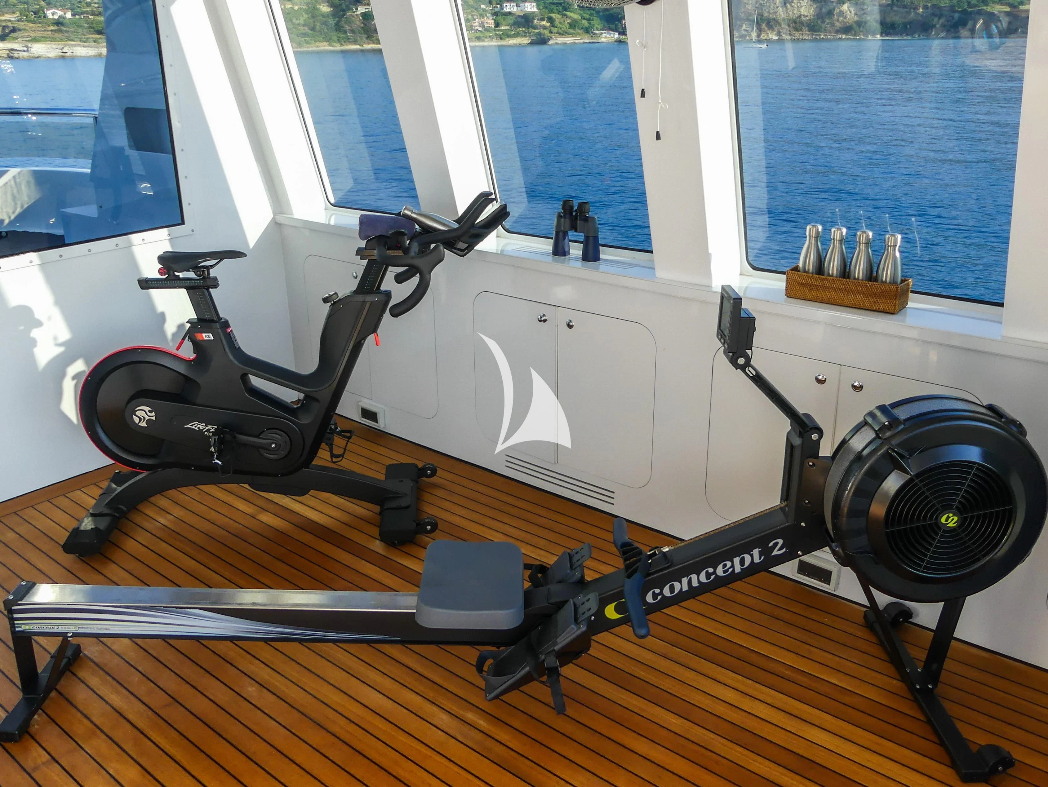 a black and white machine on a wood floor next to a window aboard CYAN Yacht for Sale
