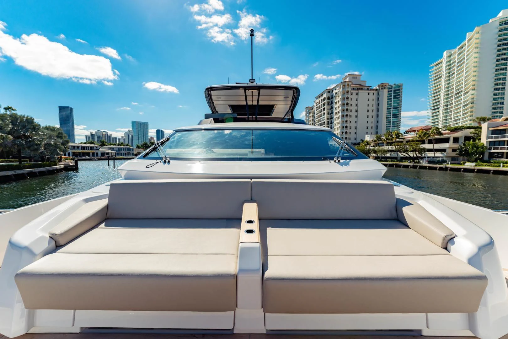 a white boat in a body of water with buildings in the background aboard BESO Yacht for Sale