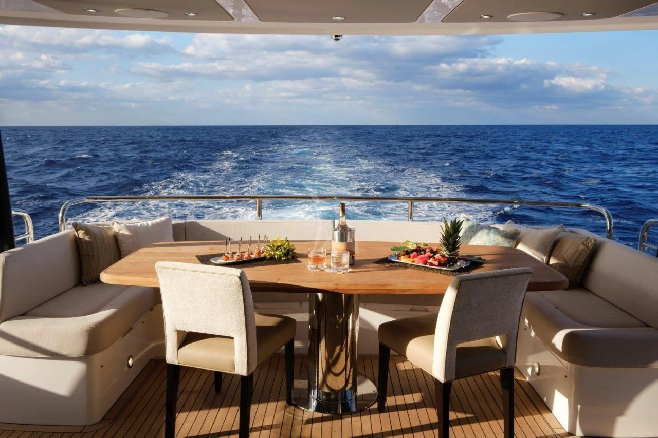 a table with chairs and a view of the ocean aboard GOLDEN OURS Yacht for Sale