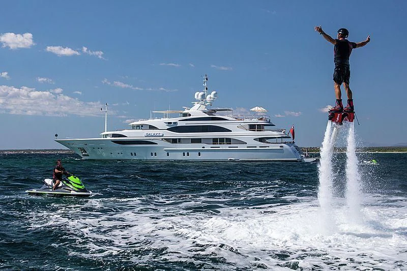 a man jumping into the water with a boat in the background aboard GALAXY Yacht for Sale