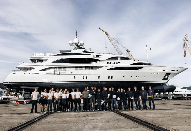 a group of people standing in front of a large military ship aboard GALAXY Yacht for Sale