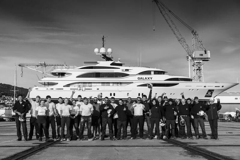 a group of people posing for a photo next to a large ship aboard GALAXY Yacht for Sale